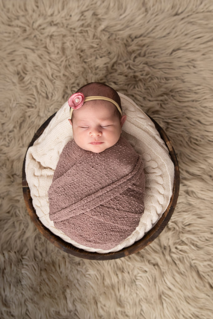 Newborn baby sleeps wrapped up in lilac wrap. 