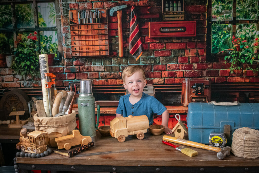 Happy child playing with wooden truck in a workshop